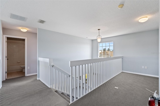 hall featuring carpet floors and a textured ceiling