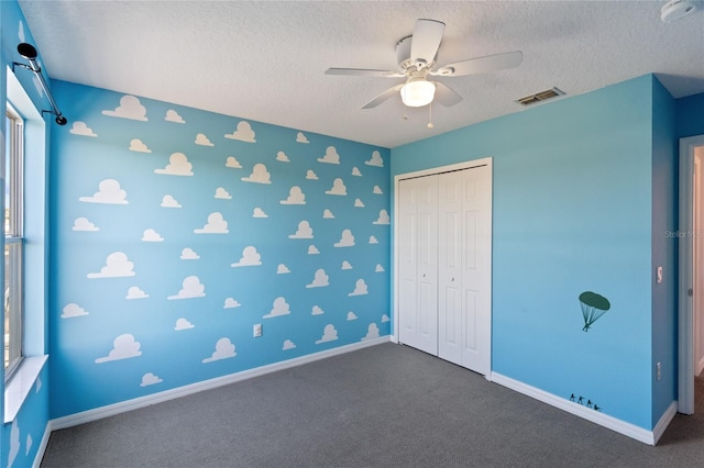 unfurnished bedroom featuring multiple windows, ceiling fan, a closet, and a textured ceiling