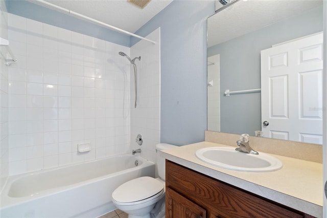 full bathroom with tiled shower / bath, vanity, a textured ceiling, and toilet