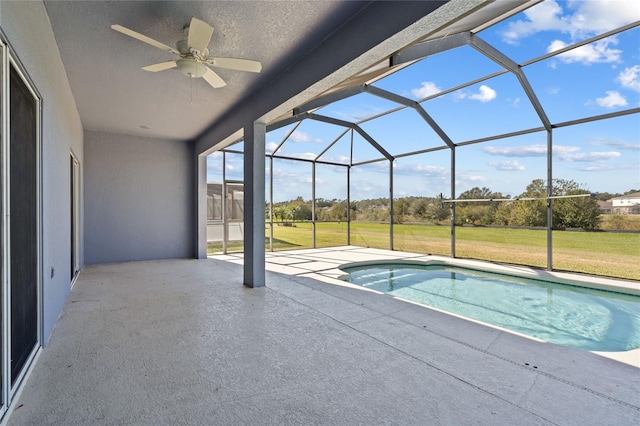 view of swimming pool featuring ceiling fan, a patio area, a yard, and glass enclosure