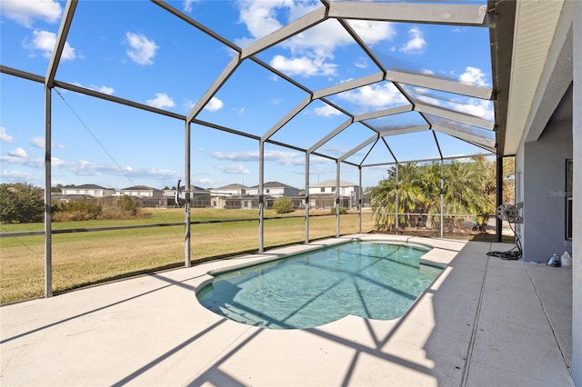 view of pool with a lawn, glass enclosure, and a patio