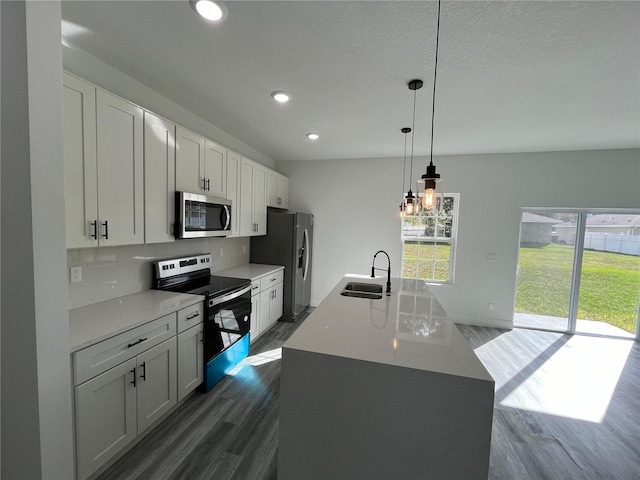 kitchen with pendant lighting, sink, white cabinets, and stainless steel appliances