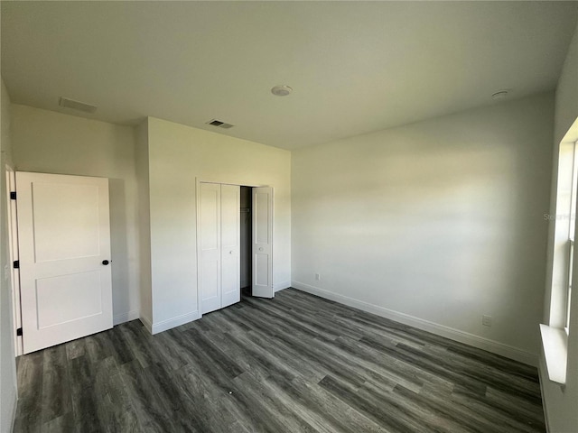 unfurnished bedroom with a closet and dark wood-type flooring