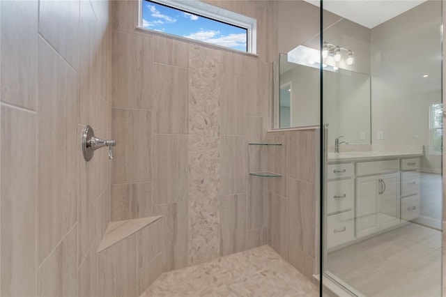 bathroom with a tile shower and vanity