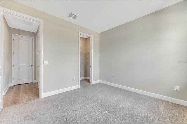 unfurnished bedroom featuring carpet, a walk in closet, and a closet