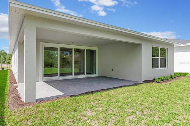 back of property featuring a lawn and a patio area