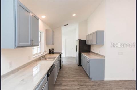 kitchen featuring gray cabinets, sink, hardwood / wood-style floors, and appliances with stainless steel finishes