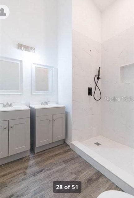 bathroom featuring a tile shower, vanity, hardwood / wood-style flooring, and toilet