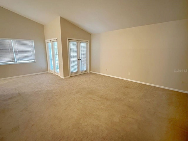 unfurnished room with vaulted ceiling, light carpet, and french doors