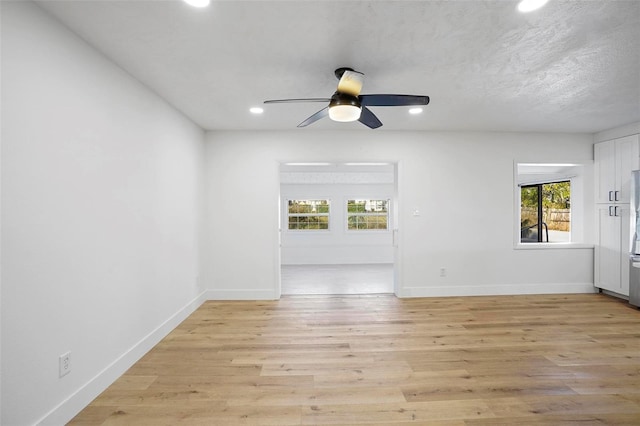 empty room with ceiling fan, a textured ceiling, and light hardwood / wood-style flooring