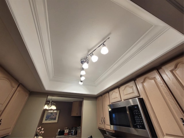 kitchen featuring a raised ceiling, light brown cabinets, ornamental molding, and an inviting chandelier