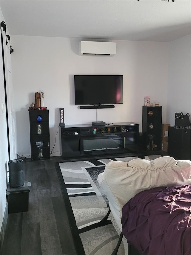 living room featuring wood-type flooring, a barn door, and a wall unit AC