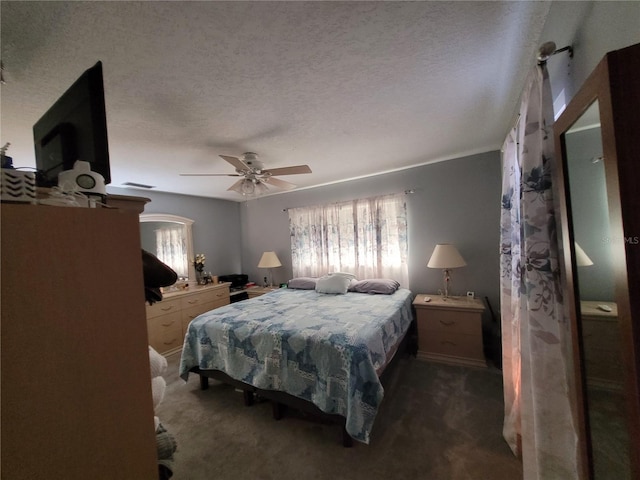 bedroom featuring a textured ceiling, dark carpet, and ceiling fan