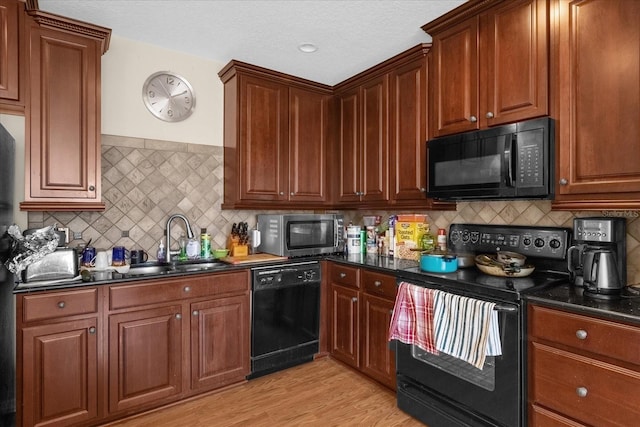 kitchen with tasteful backsplash, sink, black appliances, light hardwood / wood-style flooring, and dark stone countertops