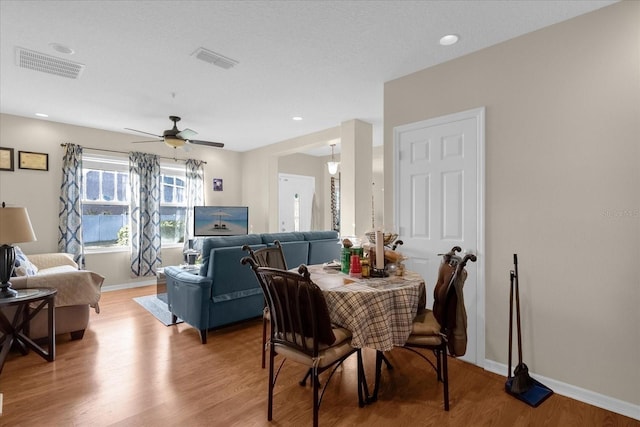 dining space with ceiling fan, wood-type flooring, and a textured ceiling