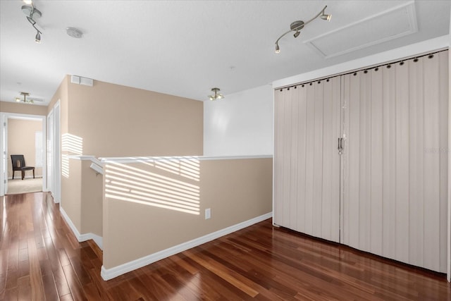 hallway with dark hardwood / wood-style floors and track lighting