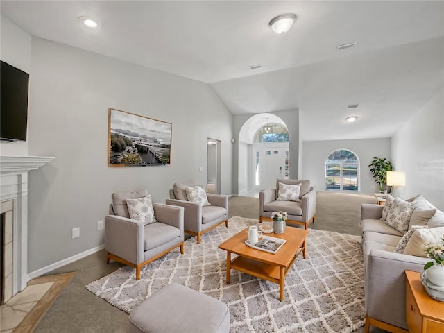 carpeted living room featuring a tiled fireplace and vaulted ceiling