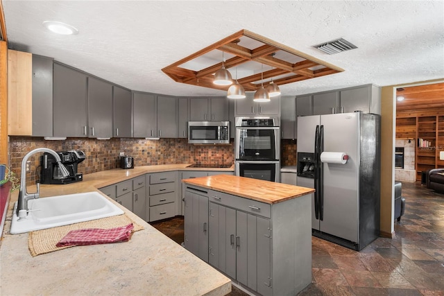 kitchen featuring sink, stainless steel appliances, a textured ceiling, gray cabinets, and a kitchen island