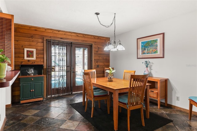 dining space with wood walls and an inviting chandelier