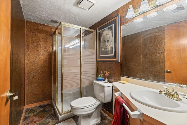 bathroom featuring vanity, toilet, a shower with door, and a textured ceiling