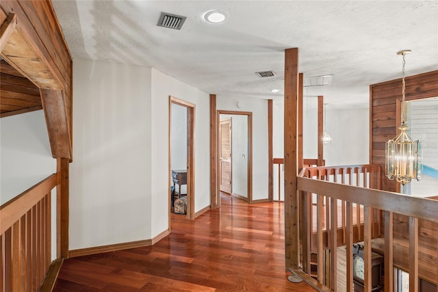 corridor featuring a chandelier, a textured ceiling, and dark hardwood / wood-style floors