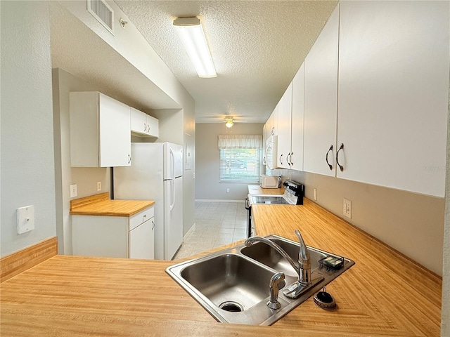 kitchen with white cabinetry, sink, a textured ceiling, white appliances, and light tile patterned flooring