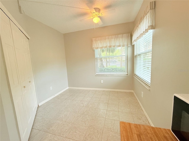 tiled spare room featuring ceiling fan and a textured ceiling