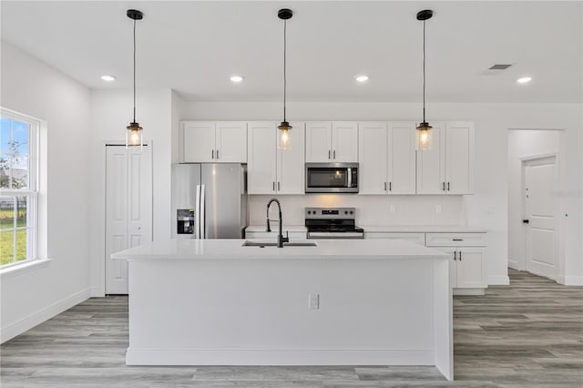 kitchen with white cabinets, a kitchen island with sink, stainless steel appliances, and a wealth of natural light