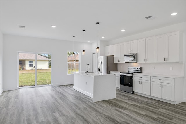 kitchen featuring light hardwood / wood-style flooring, stainless steel appliances, hanging light fixtures, and an island with sink