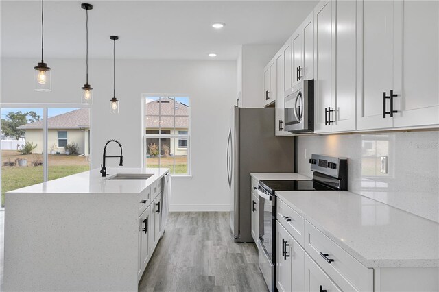 kitchen with decorative light fixtures, sink, white cabinetry, and stainless steel appliances