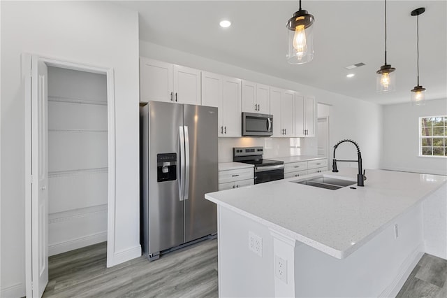 kitchen featuring sink, decorative light fixtures, a kitchen island with sink, white cabinets, and appliances with stainless steel finishes