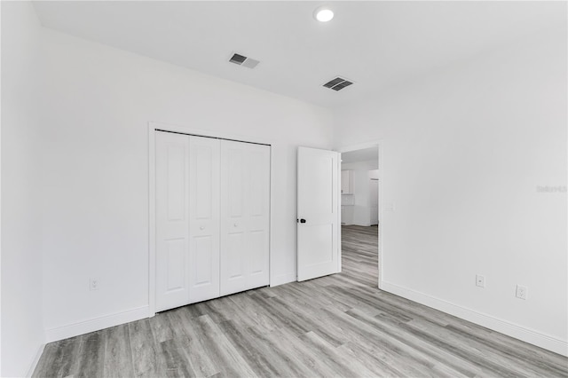 unfurnished bedroom featuring light hardwood / wood-style flooring and a closet