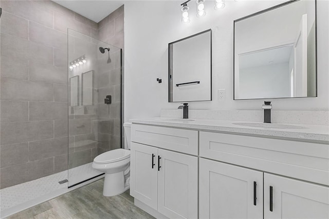 bathroom with hardwood / wood-style floors, vanity, toilet, and a shower with shower door