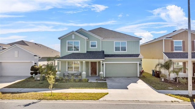 traditional home featuring an attached garage, a shingled roof, a porch, and concrete driveway