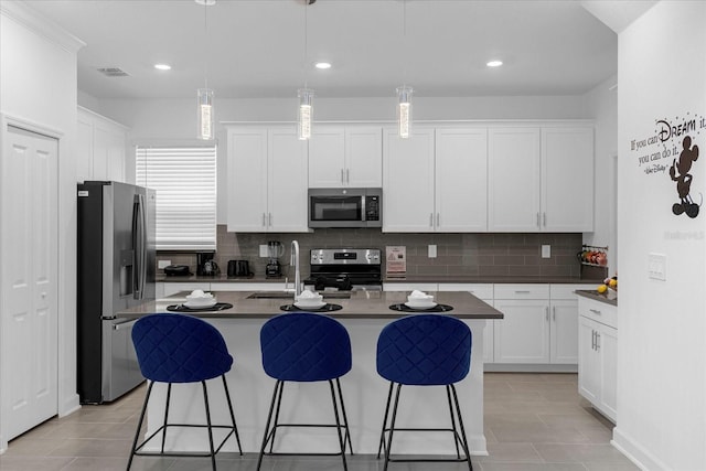 kitchen featuring white cabinets, a kitchen island with sink, hanging light fixtures, and appliances with stainless steel finishes