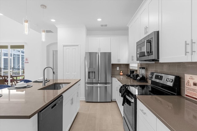 kitchen featuring stainless steel appliances, sink, white cabinets, hanging light fixtures, and an island with sink