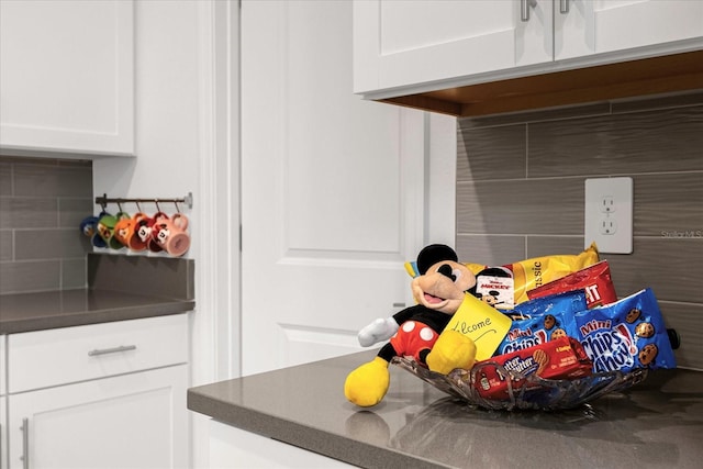 interior details featuring decorative backsplash and white cabinets