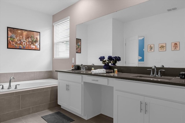 bathroom featuring tile patterned flooring, vanity, and tiled bath