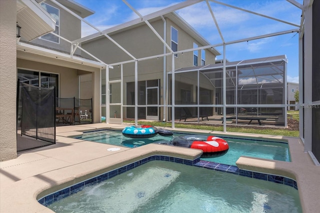 view of swimming pool featuring glass enclosure, an in ground hot tub, and a patio