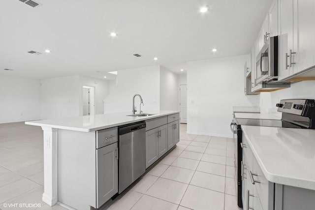 kitchen with stainless steel appliances, gray cabinets, a kitchen island with sink, and sink