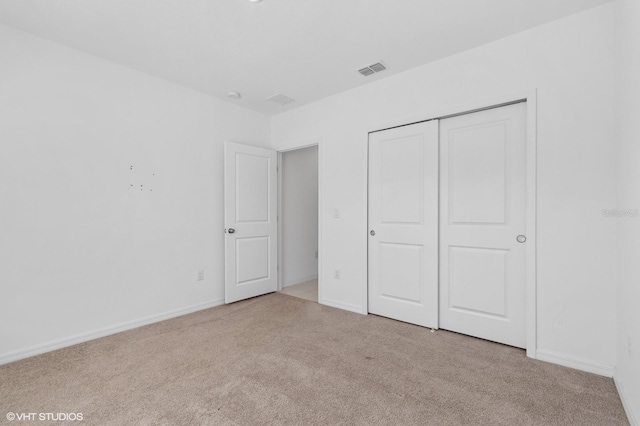 unfurnished bedroom featuring light carpet and a closet