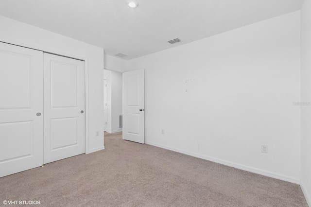 unfurnished bedroom featuring light colored carpet and a closet