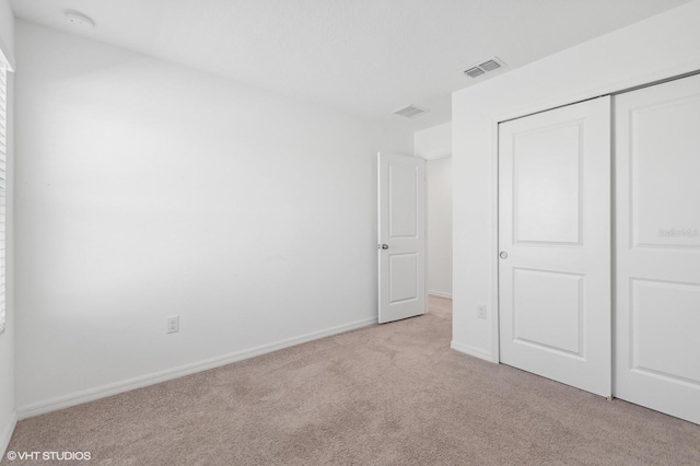 unfurnished bedroom featuring light colored carpet and a closet