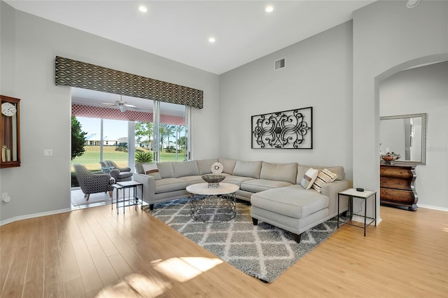 living room featuring ceiling fan, hardwood / wood-style floors, and a high ceiling