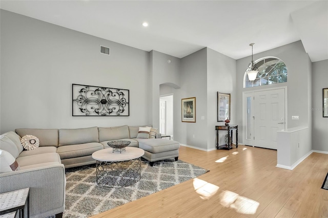 living room featuring high vaulted ceiling and light hardwood / wood-style flooring