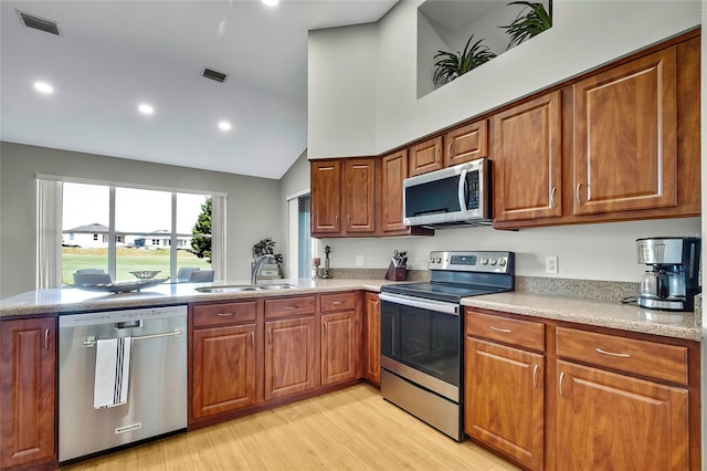 kitchen featuring kitchen peninsula, appliances with stainless steel finishes, sink, high vaulted ceiling, and light hardwood / wood-style floors