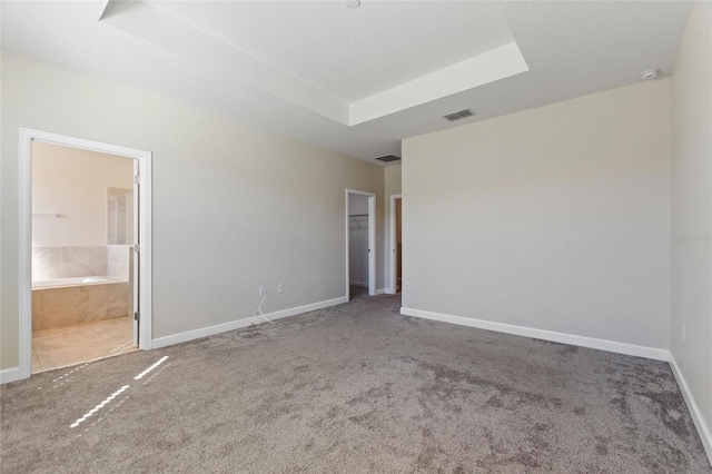 carpeted empty room featuring a raised ceiling and a textured ceiling