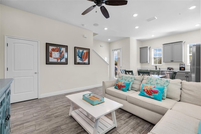 living room with ceiling fan, sink, and light hardwood / wood-style flooring