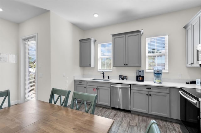 kitchen with gray cabinetry, sink, light hardwood / wood-style flooring, and appliances with stainless steel finishes