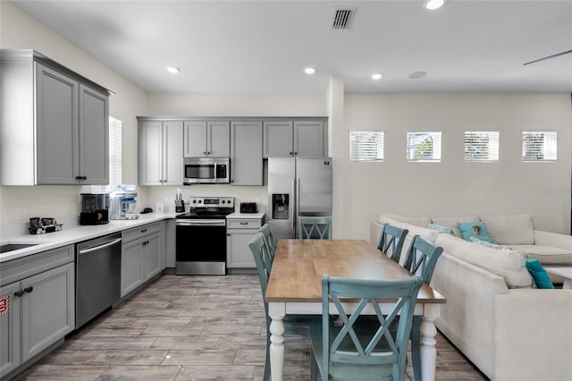 kitchen with appliances with stainless steel finishes, light wood-type flooring, and gray cabinets